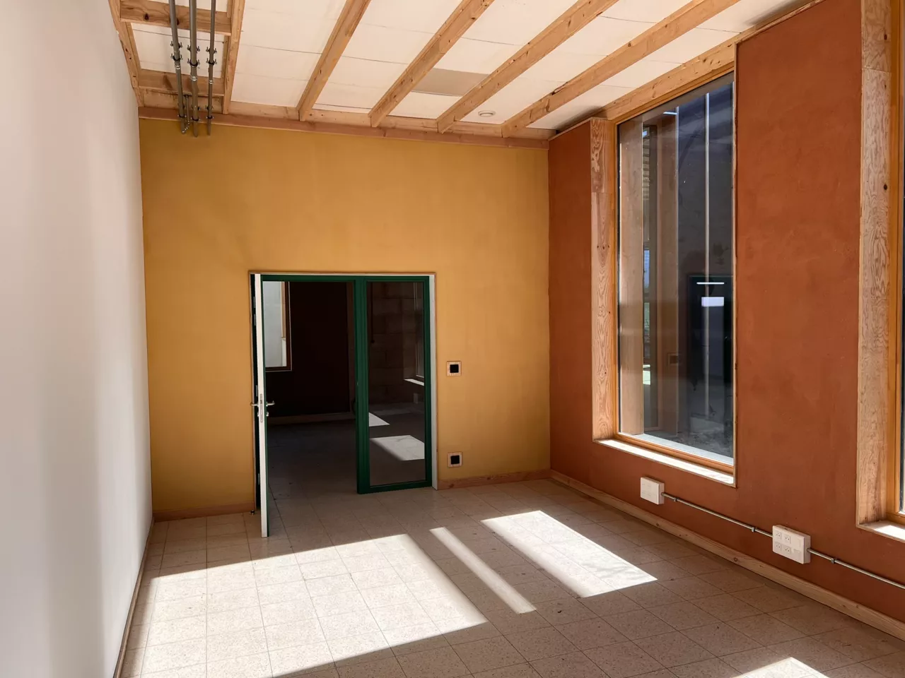 Mur avec enduit en terre crue intégrant un serpentin à eau chaude servant de mur chauffant, dans le bâtiment démonstrateur de Noeux-environnement. Une solution biosourcée innovante alliant confort thermique, esthétique naturelle et performance énergétique.